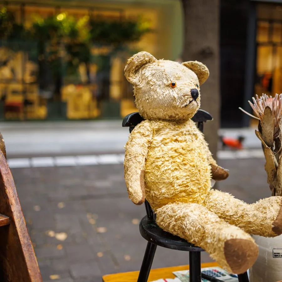Vintage golden teddy bear sitting on a small chair
