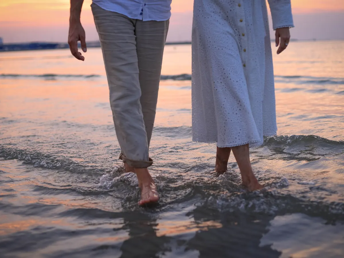 Two people walking barefoot at the water's edge