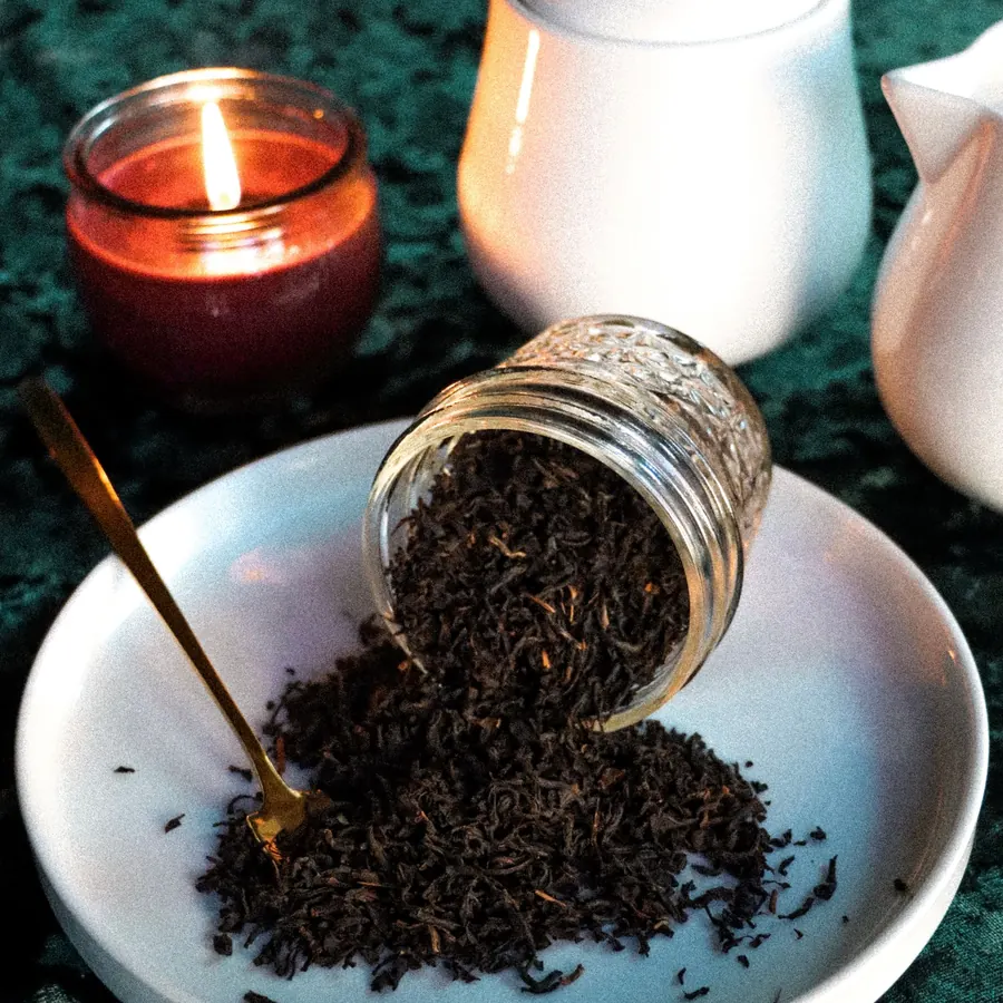 Black tea spilling from a jar by candlelight