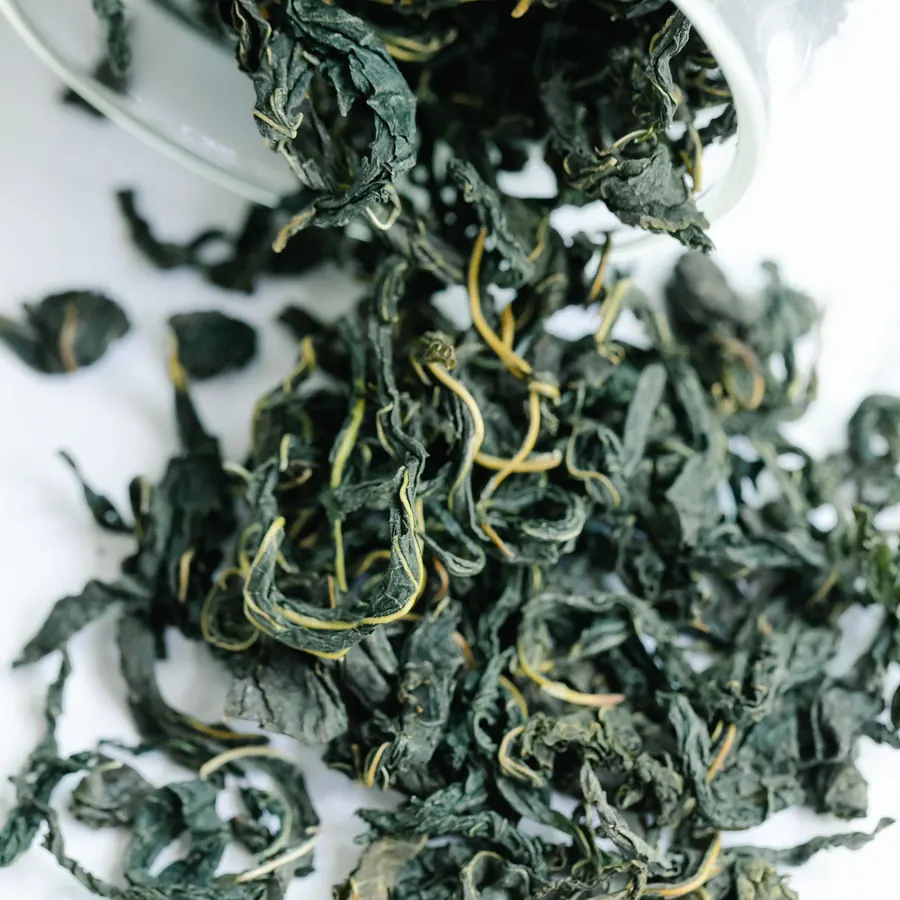 Green tea leaves spilling from a jar
