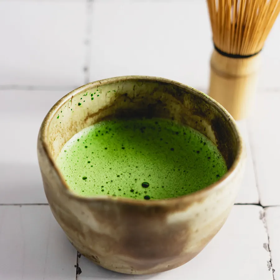 Matcha in a bowl with a bamboo whisk
