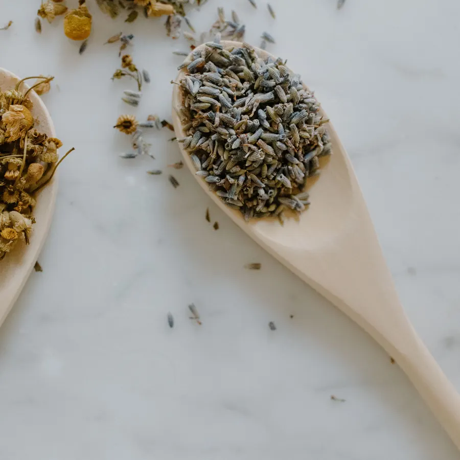 Dried lavender and chamomile on wooden spoons