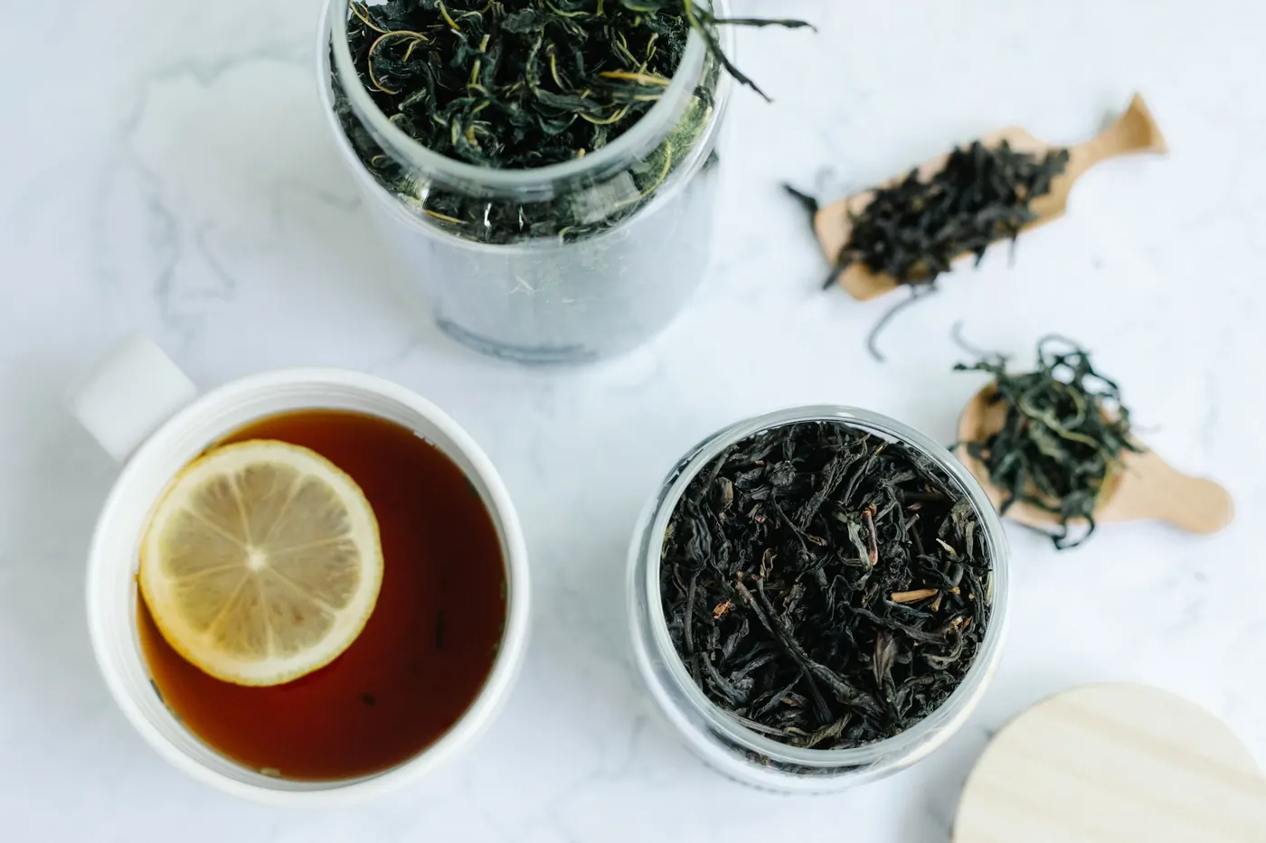 Cup of tea with lemon and jars of loose tea