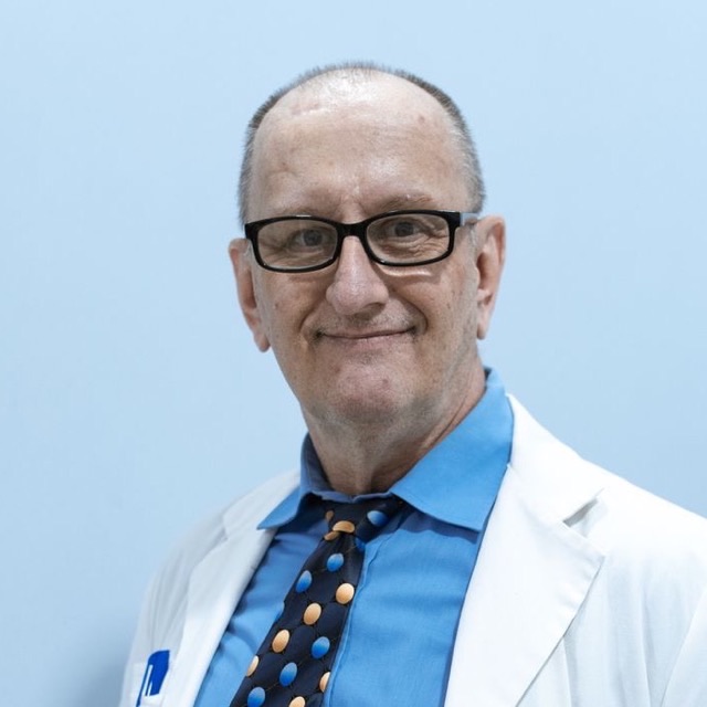 Portrait of a senior plastic surgeon with glasses in a white coat